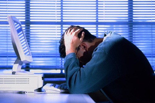 man at computer holding head in hands while trying to develop an app