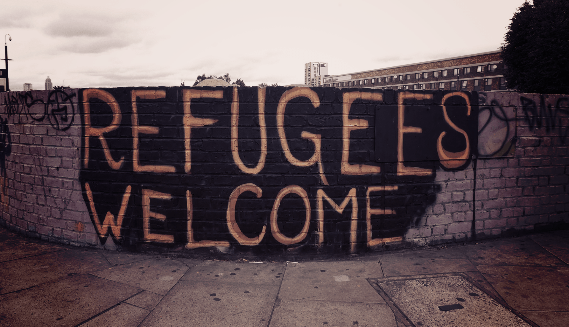 wall with spraypaint message reading Refugees Welcome