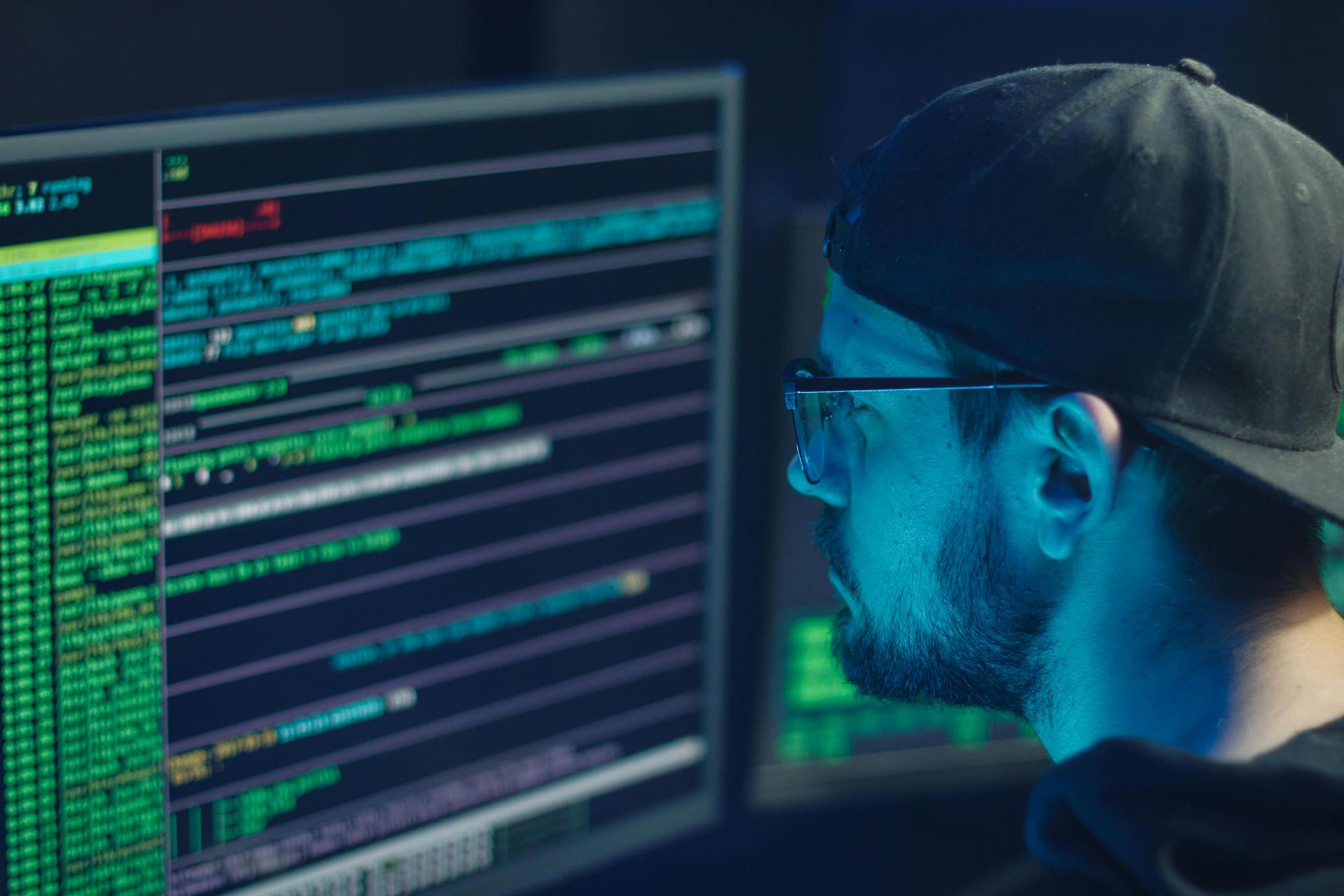 Man with glasses at computer looking at code.