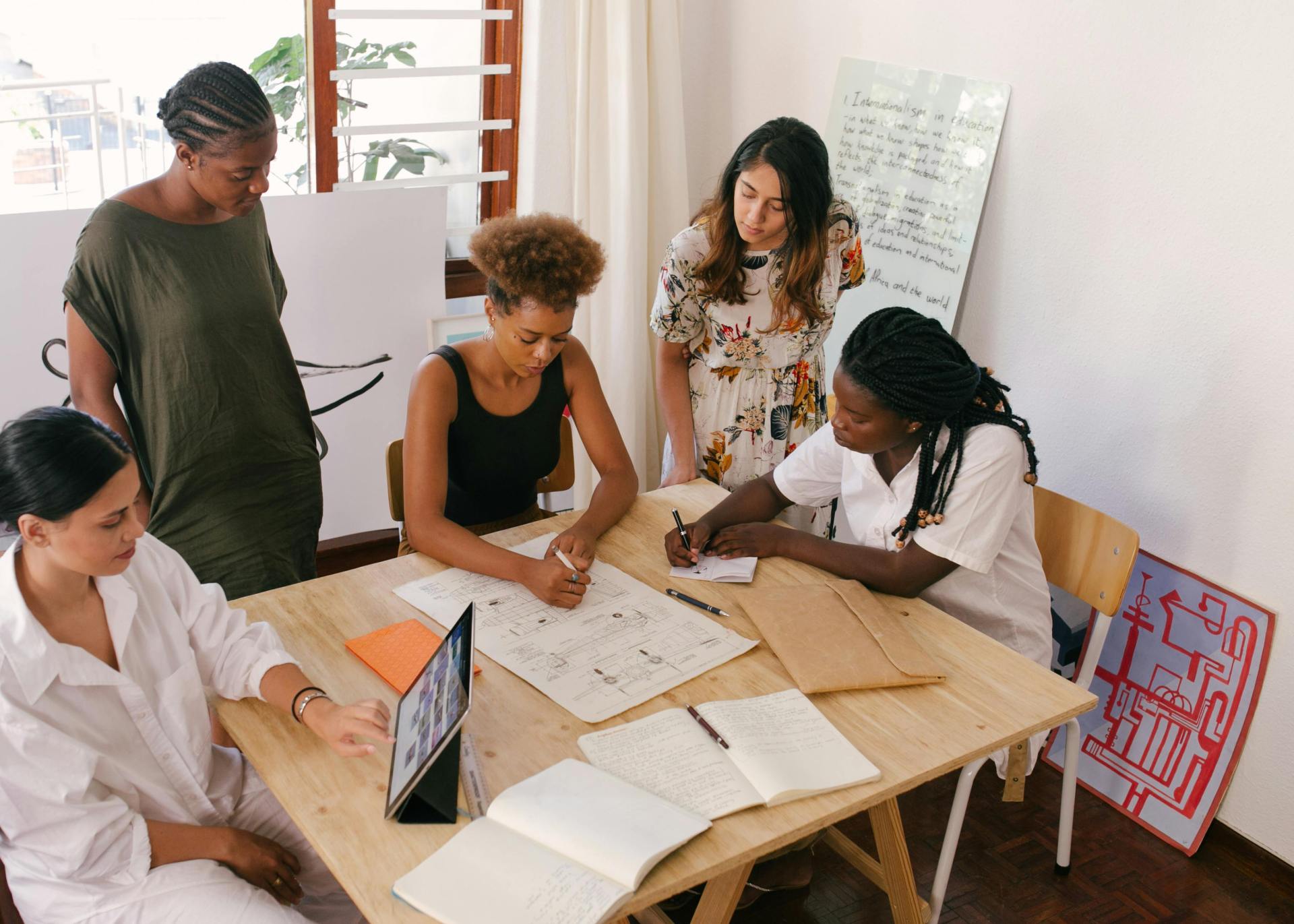 People in office strategizing a plan on tablet and paper.