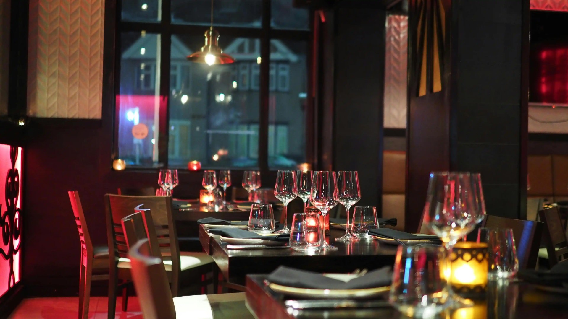 A fine dining restaurant at night, with empty tables and nice table settings.